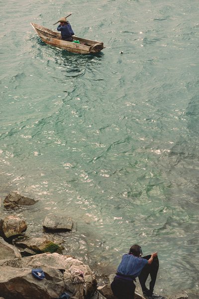 man paddling canoe and woman washing clothes on lake atitlan