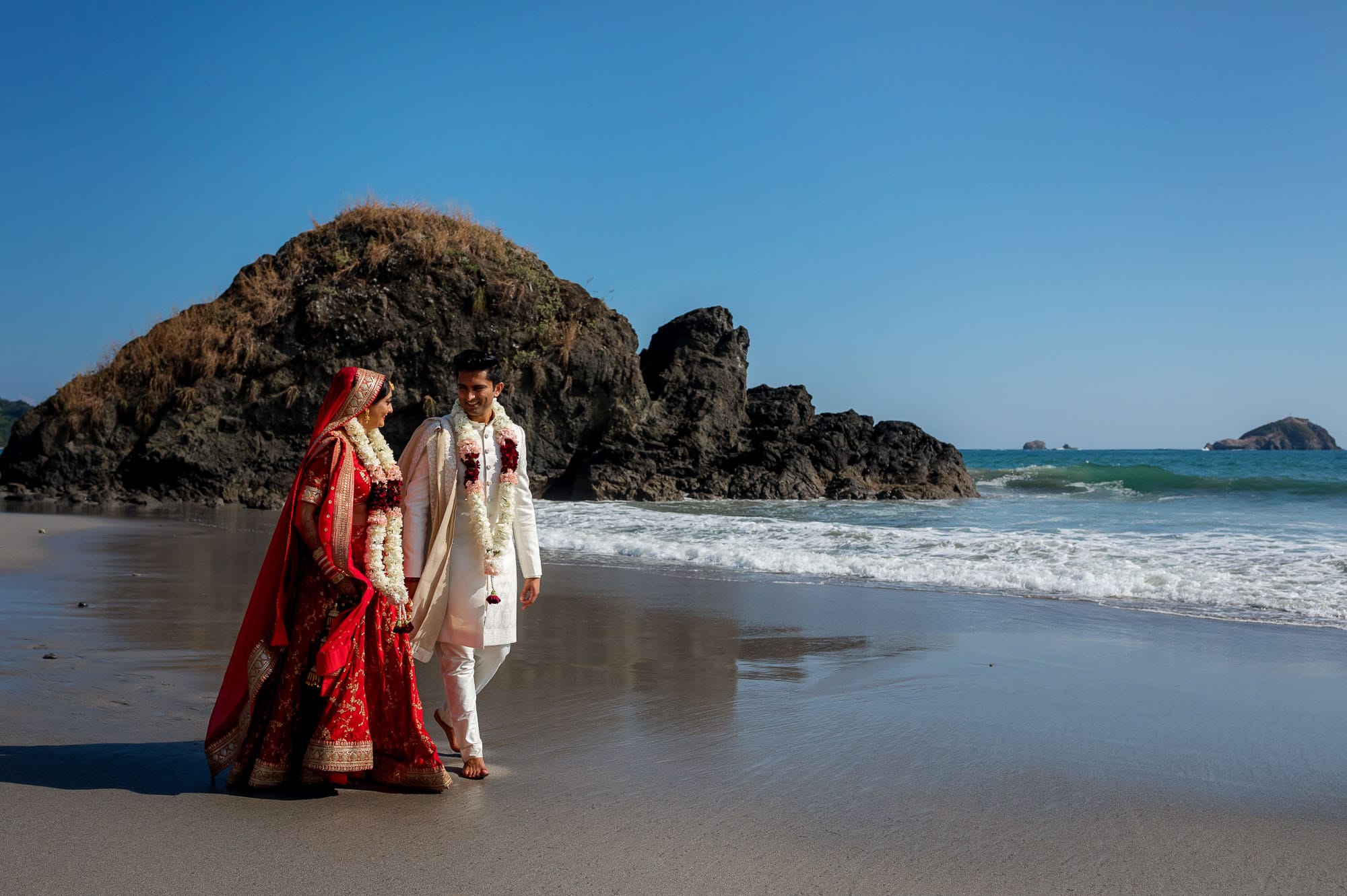 The bride and groom on the beach in traditional Hindu garb