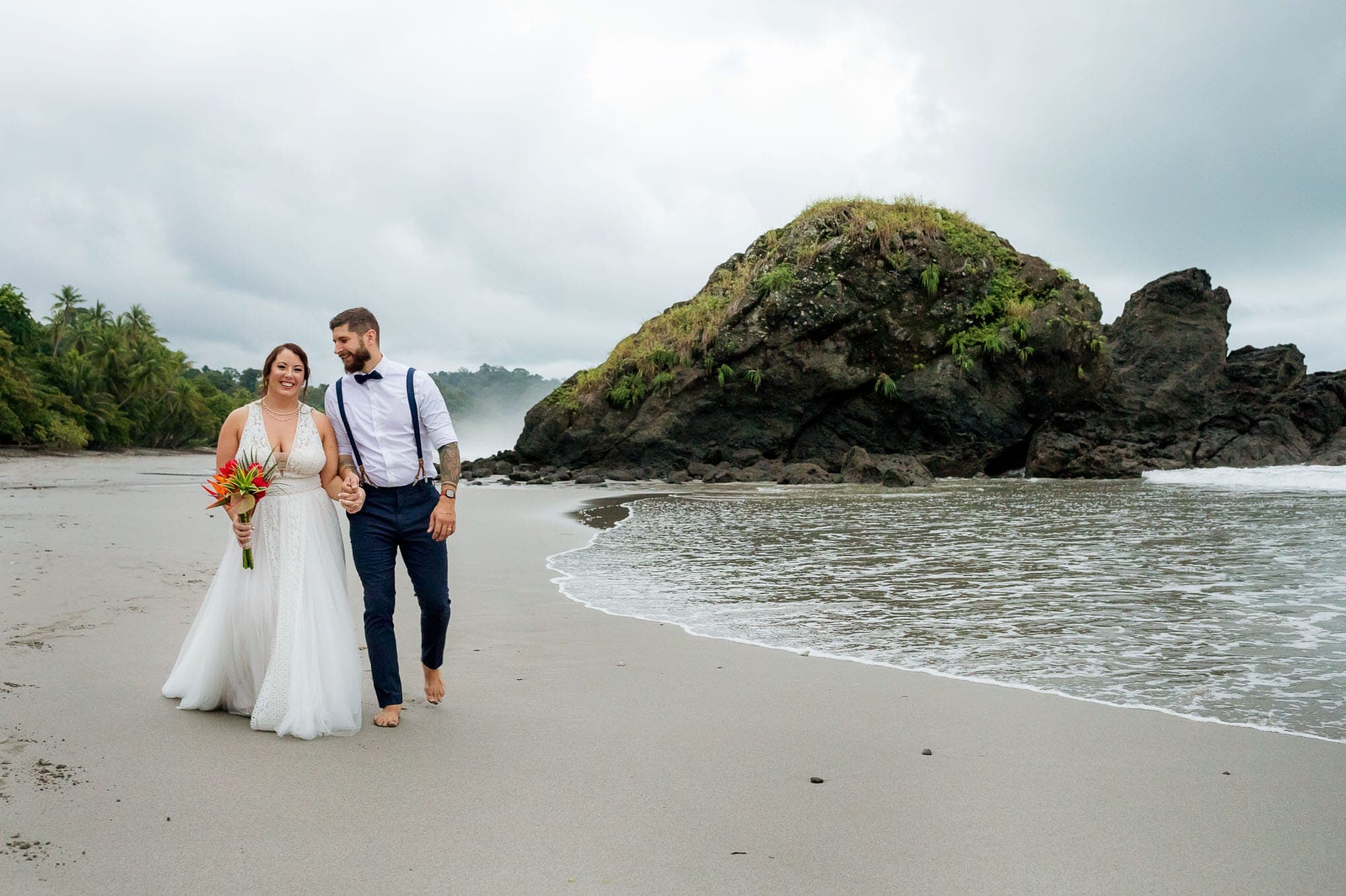Bride and groom walk along the beach
