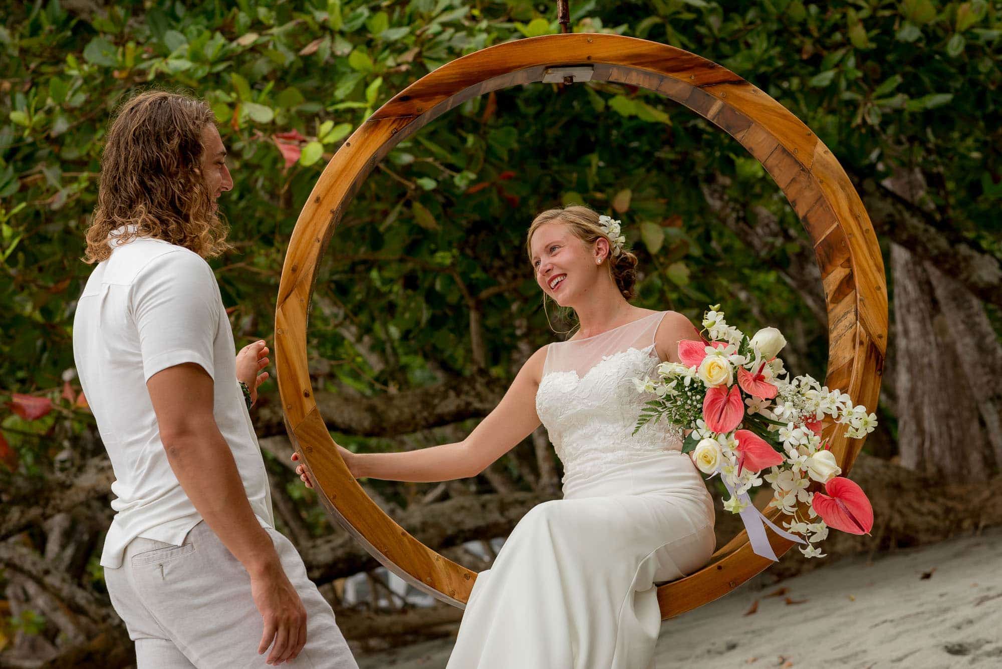 Bride seated in a circle swing with groom at her side