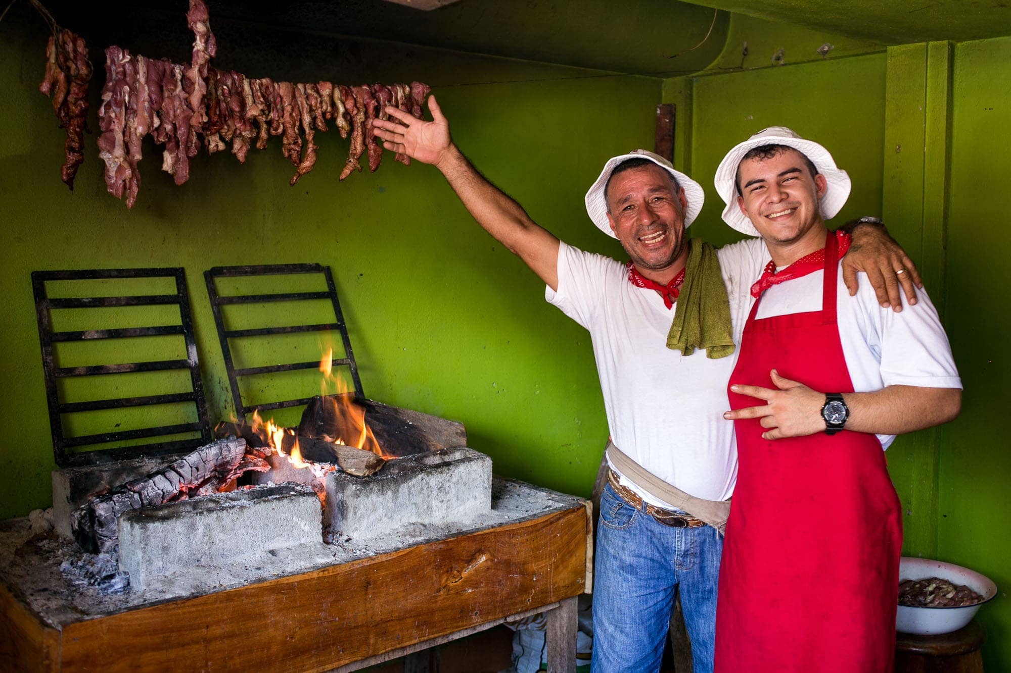 Happy men in traditional Costa Rican garb grilling meat for the pinches